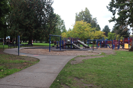 Children's playground with bark chip and mat surface – partial sidewalk – playgrounds in two locations